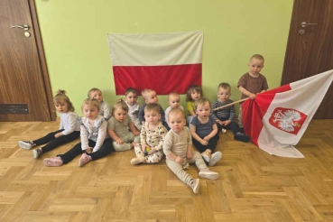 Dzieci w siedzą na podłodze, chłopczyk z polską flagą