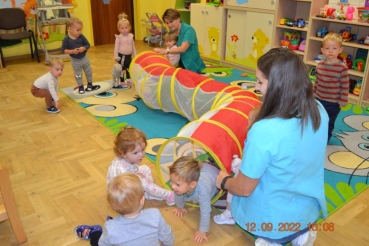 Dzieci bawią się w kolorowym tunelu wraz z opiekunkami