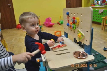Chłopiec bawi się zabawkowym stołem warsztatowym